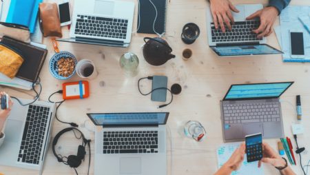 A photo of different laptops on a table for collaborative working